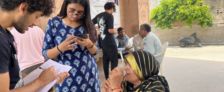 Volunteers noting an elderly woman's details outdoors during a community survey